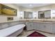 Bathroom with tub and separate vanities with granite counters and decorative mirrors at 9341 Blind Pass Rd, St Pete Beach, FL 33706