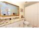 Bathroom with granite countertop, large framed mirror, toilet and shower with white curtain at 9341 Blind Pass Rd, St Pete Beach, FL 33706