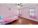 Bright bedroom featuring hardwood floors, a ceiling fan, and two windows with pink curtains at 11001 Hobson St, Spring Hill, FL 34608