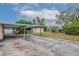View of a paved carport extending from the house, leading to a backyard shed and grassy yard at 3916 W Oklahoma Ave, Tampa, FL 33616