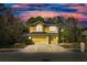 Charming two-story home with a three car garage and a beautifully landscaped yard under a dramatic twilight sky at 587 Lakewood Dr, Oldsmar, FL 34677