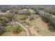 Expansive aerial shot showcases a property with a pond and a wooded area, accessible by a dirt road at 3009 Jim Johnson Rd, Plant City, FL 33566