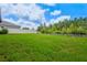 Large grassy backyard with a white fence and a view of the surrounding green trees at 21812 Emory Oak Pl, Land O Lakes, FL 34637