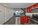 Modern kitchen featuring stainless steel appliances, red cabinetry, and stylish backsplash, with views of the stairwell and living space at 2424 W Tampa Bay Blvd # B201, Tampa, FL 33607