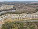 An aerial view of a community showcasing well-maintained homes with a community pond and scenic wooded backdrop at 13456 Marble Sands Ct, Hudson, FL 34669