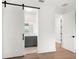 Modern bathroom featuring a barn door, gray vanity, and lighted mirror, blending style and functionality at 1046 Bass Blvd, Dunedin, FL 34698