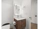 Bathroom with modern sink, lit mirror, wood grain cabinet, and a toilet on luxury vinyl plank flooring at 1046 Bass Blvd, Dunedin, FL 34698