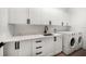 Well-organized laundry room with white cabinetry, quartz countertops, sleek black hardware, and modern washer and dryer set at 1046 Bass Blvd, Dunedin, FL 34698
