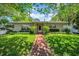 Charming single-story home with a well-maintained lawn and brick walkway, shaded by mature trees, offering curb appeal at 216 21St Ne Ave, St Petersburg, FL 33704
