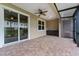 View of a covered screened patio with brick flooring, ceiling fan, storage and view to yard at 1264 Riserva Ln, Palm Harbor, FL 34683