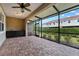 Screened patio with brick flooring, ceiling fan, storage cabinet and outdoor view at 1264 Riserva Ln, Palm Harbor, FL 34683
