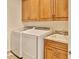 Convenient laundry room featuring modern washer and dryer units, along with a utility sink and storage cabinets at 3222 W Empedrado St, Tampa, FL 33629