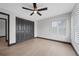 Bright bedroom featuring wood-look floors, ceiling fan, plantation shutters, and closet with black trim and doors at 5809 Cruiser Way, Tampa, FL 33615