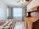 Cozy bedroom featuring wood-look floors, a window with curtains, and a vintage dresser, creating a warm ambiance at 8330 Vendome N Blvd, Pinellas Park, FL 33781