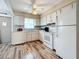 Efficient kitchen with white appliances, countertops, and cabinetry, complemented by the wood-look flooring at 8330 Vendome N Blvd, Pinellas Park, FL 33781
