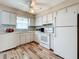 Well-maintained kitchen featuring white appliances and cabinetry, with the added touch of wood-look floors at 8330 Vendome N Blvd, Pinellas Park, FL 33781