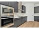 Kitchen with stainless steel appliances, sleek dark cabinetry, modern stove top and white subway tile backsplash at 8347 Golden Beach Ct, Parrish, FL 34219