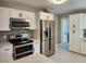 Modern kitchen with stainless steel appliances, white cabinetry, and gray subway tile backsplash at 907 Knollwood Dr, Dunedin, FL 34698