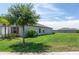 Well-maintained home exterior featuring a lush lawn and mature trees, enhancing curb appeal at 9805 Lemon Drop Loop, Sun City Center, FL 33573
