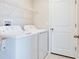 Bright laundry room features white appliances, shelving and door to the backyard at 9805 Lemon Drop Loop, Sun City Center, FL 33573