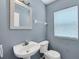 Cozy half bathroom with pedestal sink, framed mirror, and a toilet next to a window at 10815 Wrigley Ct, Riverview, FL 33579