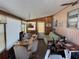A spacious living area featuring wood paneling, a dining table, a sofa, and natural light from the windows at 37402 Hammond Dr, Zephyrhills, FL 33541
