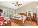 Bright primary bedroom with warm laminate flooring, a ceiling fan, and sliding glass doors to the lanai at 6009 County Line Rd, Spring Hill, FL 34606