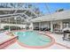 A stunning screened in pool with brick trim that features lounge chairs and a patio set at 6009 County Line Rd, Spring Hill, FL 34606