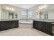 Bright bathroom with soaking tub, dark wood cabinets, and dual sinks at 10825 Charmwood Dr, Riverview, FL 33569