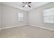 A carpeted bedroom with a ceiling fan and two windows with white blinds at 10825 Charmwood Dr, Riverview, FL 33569