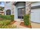 Elegant home entrance with black double doors framed by stone accents and lush landscaping at 10825 Charmwood Dr, Riverview, FL 33569