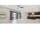 Open-concept living room with large sliding glass door to pool, ceiling fan and view into kitchen at 10825 Charmwood Dr, Riverview, FL 33569