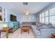 Bright living room with neutral tones, tile floors, ceiling fan, large sectional and custom built-in display shelving at 1744 Colmar Dr, Holiday, FL 34690