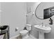 Contemporary half bathroom with a pedestal sink, round mirror, and convenient location at 29913 Southwell Ln, Wesley Chapel, FL 33543