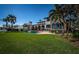 Waterfront home with a large backyard featuring a pool, lush lawn, and inviting outdoor seating area under palm trees at 3901 Bayshore Ne Blvd, St Petersburg, FL 33703