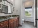 Bathroom featuring a green marble vanity top, decorative mirror, toilet, and a window at 5020 W Dickens Ave, Tampa, FL 33629