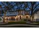 Night shot of the home featuring a three car garage and lush landscaping at 5020 W Dickens Ave, Tampa, FL 33629