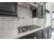 Gas cooktop with stainless steel vent hood and white subway tile backsplash at 5020 W Dickens Ave, Tampa, FL 33629