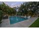 Relaxing pool area with seating, lush tropical landscaping, and travertine tile decking at 5020 W Dickens Ave, Tampa, FL 33629