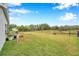 Spacious, fenced backyard with lush green grass and view of mature trees and pond at 5720 107Th E Ter, Parrish, FL 34219
