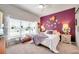 Bright bedroom with a unique purple accent wall, large window, and a ceiling fan at 5720 107Th E Ter, Parrish, FL 34219