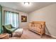 Well-lit Bedroom room with plush carpet, crib, and a comfy chair with natural light at 5720 107Th E Ter, Parrish, FL 34219
