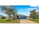Charming single-story home featuring a well-maintained lawn, colorful landscaping, and a vibrant blue garage door at 5720 107Th E Ter, Parrish, FL 34219