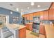 Modern kitchen includes stainless steel appliances, wood cabinets, ample counter space, and pendant lighting at 5720 107Th E Ter, Parrish, FL 34219
