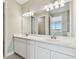 Well-lit bathroom with double vanity, framed mirrors, and modern lighting fixtures at 2416 Wise River Ln, Zephyrhills, FL 33541