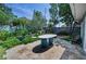 Inviting back patio showcasing travertine tile, lush landscaping, outdoor seating, and a tranquil garden setting at 546 Orangewood Dr, Dunedin, FL 34698