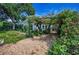 Charming home with lush landscaping, including flowering vines over an arbor at 546 Orangewood Dr, Dunedin, FL 34698