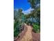 Charming backyard featuring a stone garden path, lush greenery, and colorful flowering trees at 546 Orangewood Dr, Dunedin, FL 34698