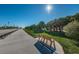 Scenic paved path featuring a wooden bench, lush grass, and palm trees under a sunny sky at 546 Orangewood Dr, Dunedin, FL 34698