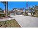 Charming two-story home showcasing a spacious driveway and a three-car garage, surrounded by lush landscaping at 5701 S Macdill Ave, Tampa, FL 33611